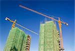 Large crane over some buildings in construction, viewed from a new finished residential district.