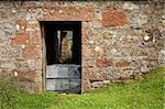 Doorway of a ruined farmhouse against grass