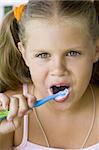 little blond girl cleaning teeth by toothbrush