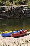 colorful touring canoes on river bank