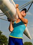 Rower girl carrying sport boat outdoors summer