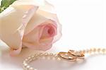 Wedding rings, pearl beads and rose over white, isolated, with clipping path