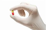 Red-and-yellow pill in nurse's hand,isolated, on white background