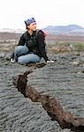 A young woman explores a crack in the lava flow