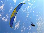 paraglide (parachute) flying under blue cloudy sky