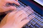 Person typing quickly on the keyboard of a computer with motion blur