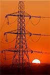 Electricity transmission pylon against a setting Sun