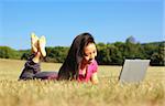 Fashionable girl working on laptop in a meadow.