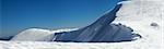 Winter mountains ridge with overhang snow caps and snowboard tracks on blue sky background (Ukraine, Carpathian Mt's, Svydovets Range, Blyznycja Mount, Drahobrat ski resort). Three shots stitch image.