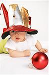Small boy in the hat of jester plays with the red sphere