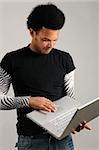 Portrait of young trendy latino man holding modern laptop computer