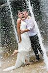 Bride and groom dancing under a water fountain on their wedding day.