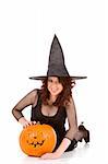 Portrait of Latina teenager girl in black Halloween hat and fishnet dress with carved pumpkin (Jack O' Lantern) (focus on pumpkin)