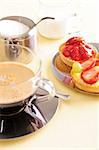 Freshly brewed coffee with a selection of pastries and cakes. Focus is on the strawberry pastry.