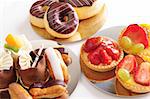 Delicious freshly baked pastries on shiny plates. White background, not isolated.