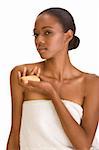 Beautiful young African-American woman with Slicked Back Hair wrapped in white bath towel an holding bar of soap preparing for sauna