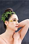 Beautiful brunette face with pink green yellow eye flower petal makeup, isolated on gray