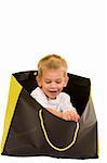 An adorable three year old playing with a shopping bag, isolated on white.