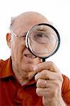 old man looking through lens against white background