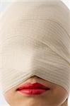 close up of woman with bandage around face and red lips