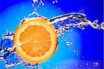 Close up view of sliced orange piece getting splashed with water