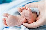 young mother holding cute newborn baby feet