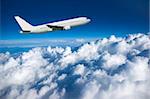 Large airliner climbing along cloud top against a deep blue sky