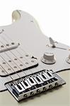 Close portrait view of the bridge and body of a white electric guitar. Isolated on white.