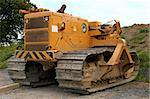 Large yellow bulldozer standing idle on rough earth.