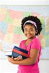 African American girl standing in front of USA map holding stack of books smiling at viewer.