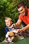Caucasian father and toddler son giving  English Bulldog a bath outdoors.