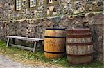 A bench and two barrels along side stone walls