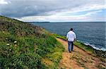 A man walking on a hiking trail along the coast of Brittany, France