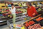 Middle aged African American woman pointing out produce in grocery store to middle aged man.