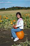 Girl in a pumpkin patch sitting and smiling.