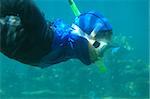 A man in a mask snorkeling underwater close-up.