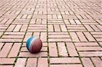 A small ball laying on a pavement tiles.