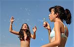 Two girls playing with bubbles on the beach