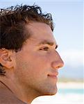 Head and shoulder profile portrait of handsome man on beach.