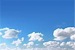 Background of light blue sky with white fluffy clouds at the bottom