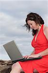 Lady in red dress typing on a laptop