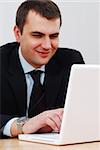 Young businessman working on lap-top and smiling
