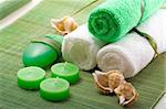 Spa concept of green color: the towel, soap and candles over sisal background