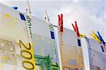 Euro banknotes on a clothesline against cloudy sky