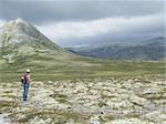 Woman contemplating the wilderness in a national park while making a pause from hiking - Rondane - Norway
