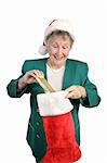 An excited senior woman opening her Christmas stocking.  Isolated on white.