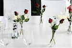 Elegant table setting with vases of red roses and white linen.