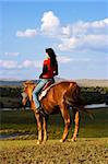 An asian girl horse riding at the grassland.