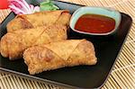 Crispy Chinese egg rolls with sweet, tangy chili sauce for dipping.