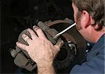 An auto mechanic removing the brake housing from a front disc brake.